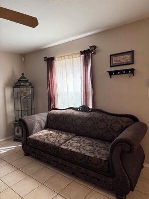 A living room with a patterned sofa, a decorative lantern, and a wall-mounted shelf. - 2-bedroom townhome in pleasant Harlingen. Sleeps 6  (Harlingen)
