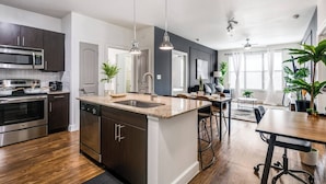 Une cuisine moderne avec des meubles de couleur sombre, des appareils électroménagers en acier inoxydable et un plan de travail en granit.