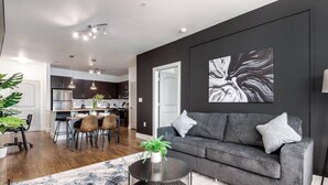 Un salon moderne avec un canapé gris, une table basse ronde et un grand tableau abstrait accroché au mur.