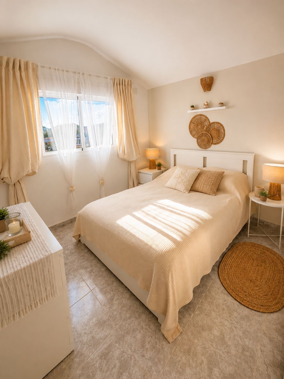 A bedroom with a large bed, bedside tables, a bedside lamp, a small plant, and a window with curtains.