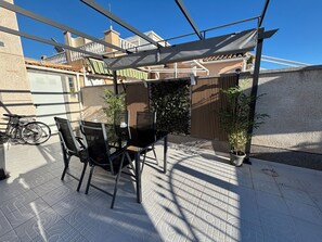 Eine Terrasse im Freien mit Tisch, Stühlen, einem Fahrrad und einem Blumentopf.