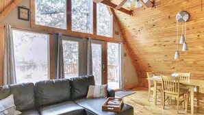 Una habitación acogedora con un sofá seccional, una mesa de comedor con sillas y ventanas grandes que dejan entrar luz natural.