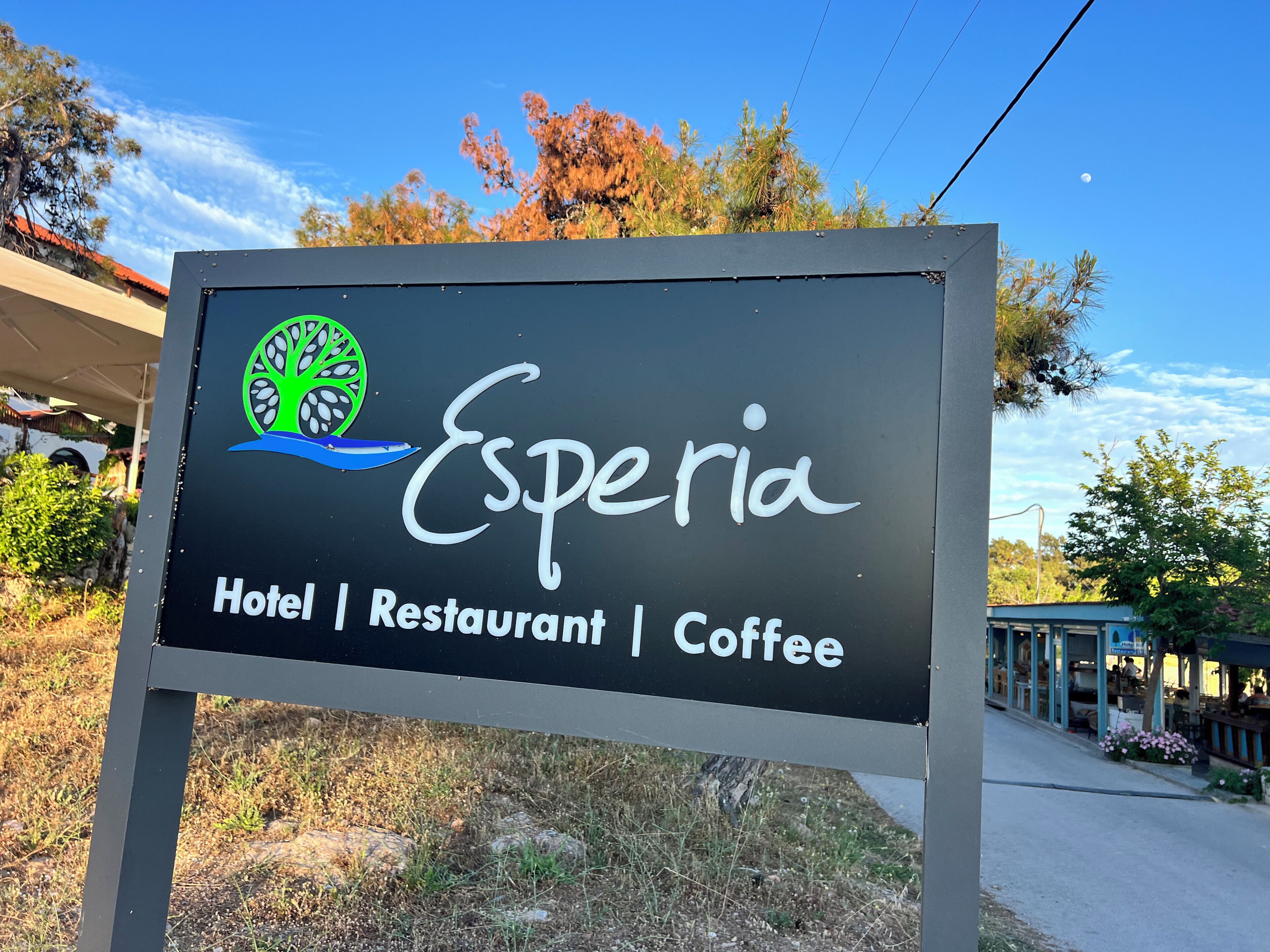 A sign for 'Esperia Hotel | Restaurant | Coffee' with a logo featuring a tree and a blue wave.