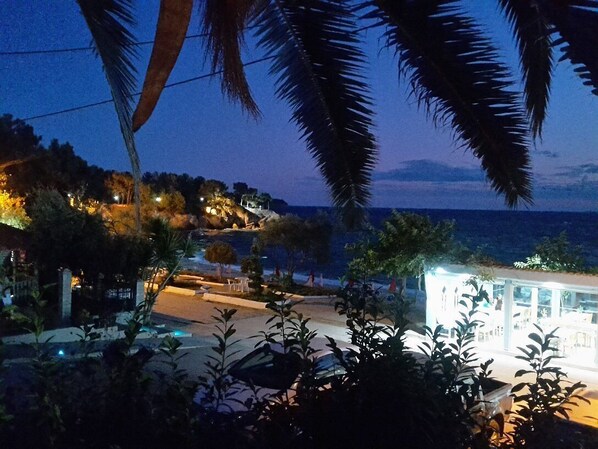 A coastal hotel with a view of the sea, surrounded by palm trees and a well-lit outdoor area. - HOTEL ESPERIA (Thasos)