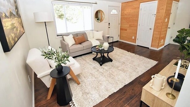 Een moderne woonkamer met een bank, salontafel en een bijzettafeltje met een plant.