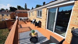 Een terras met buitenmeubilair, een barbecue en een schuifpui.