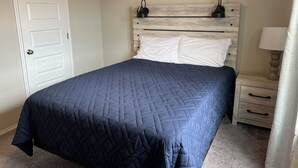 Une chambre à coucher avec un lit, une table de chevet, une lampe et une porte.