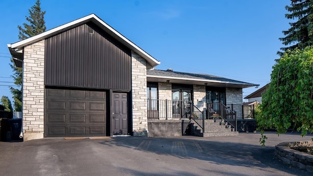 A modern two-story house with a garage, a covered porch, and a staircase leading to the second floor. - Havre d'Abraham residence (Laval)