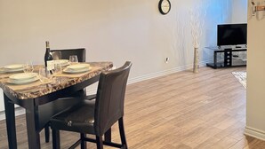 A dining area with a marble table, dark chairs, and a chandelier. - Havre d'Abraham residence (Laval)
