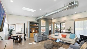 Una sala de estar moderna con comedor, chimenea y ventanas amplias.