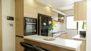 Eine moderne Küche mit Holzschränken, einem schwarzen Kühlschrank, einem Herd und einer Vase mit Blumen auf der Arbeitsplatte.