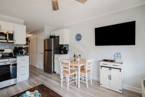 Una cocina moderna con armarios blancos, microondas integrado y un refrigerador de acero inoxidable.