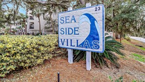 A sign for 'Sea Side Villas' with a number '23' on it, surrounded by greenery and trees. - Steps to the Surf! Top-Floor Condo w/Stunning Ocean View! (Hilton Head Island)