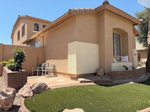 A house with a patio, a small garden, and a view of another building.