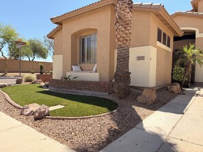 A house with a patio, a palm tree, and a well-maintained lawn.