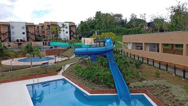 A pool area with a water slide, a swimming pool, and surrounding greenery. - Apartasol La Tebaida, Quindío (La Tebaida)