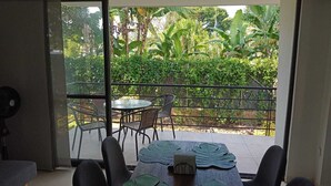 A balcony with a table and chairs, a fan, and a view of greenery and trees. - Apartasol La Tebaida, Quindío (La Tebaida)