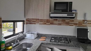 A kitchen with a microwave, stove, sink, and a window with a view of the street. - Apartasol La Tebaida, Quindío (La Tebaida)