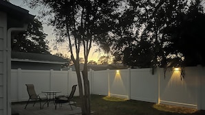 Ein Garten mit weißem Zaun, einem Tisch und Stühlen.