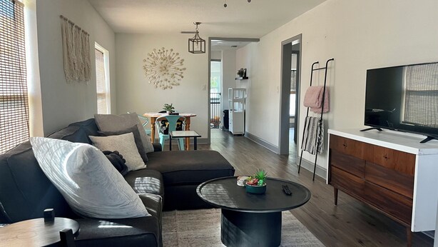 Ein modernes Wohnzimmer mit einem Ecksofa, einem Couchtisch und einem Fernseher auf einem Schrank.