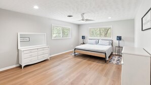 Un dormitorio con cama, cómoda, dos mesitas de noche y ventilador de techo.