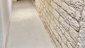 A narrow hallway with a stone wall and a wooden door at the end.