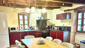 A rustic kitchen with a wooden table and chairs, a microwave, a stove, and a sink.