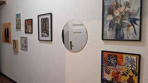 A hallway with various framed artworks on the walls, a round mirror, and a door. - Children welcome! Spacious family apartment 5 minutes from the center (Lübben (Spreewald))