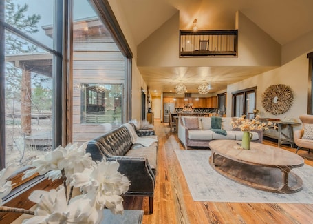 A spacious living area with a large window, a fireplace, and a kitchen in the background.