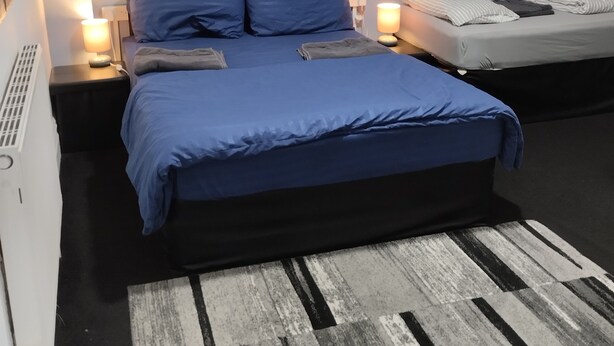 Une chambre à coucher avec un lit, des tables de chevet, une lampe et un tableau accroché au mur.