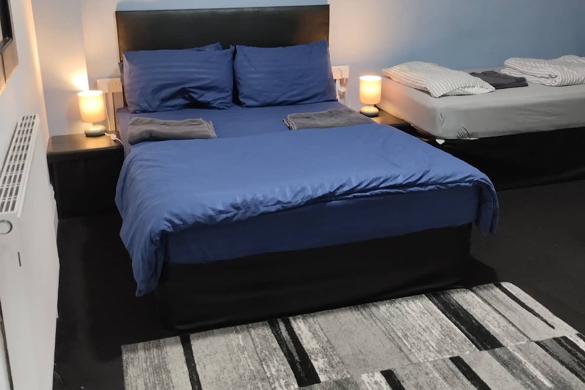 A bedroom with a bed, bedside tables, a lamp, and a wall-mounted picture.