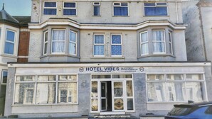 Un immeuble de deux étages, avec une enseigne indiquant « HOTEL VIBES » à l’entrée.