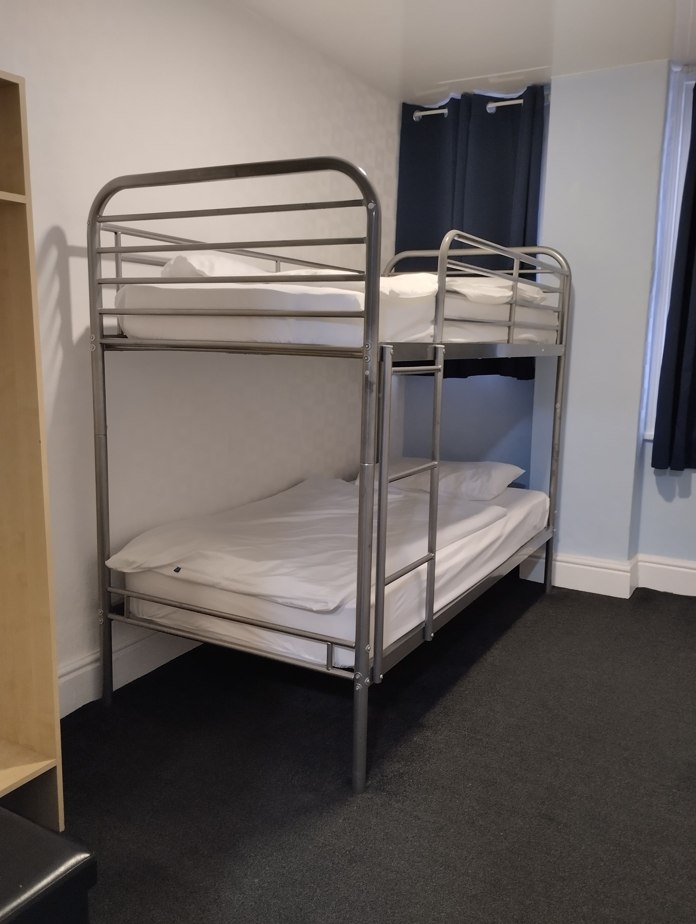 A bunk bed with metal railings and white bedding.