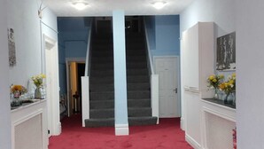 Un couloir recouvert d’une moquette rouge menant à un escalier.
