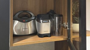 A kitchen with a wooden cabinet containing a coffee maker, a blender, and a kettle. - Modern Smart Home w/ Office, Pool, Gym & Fast WiFi - 10 min to Airport (Tunis)