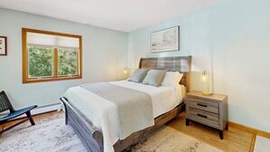 A bedroom with a bed, bedside tables, a chair, and a window. - Hilltop Family Escape | River Rock Fireplace (Naples)