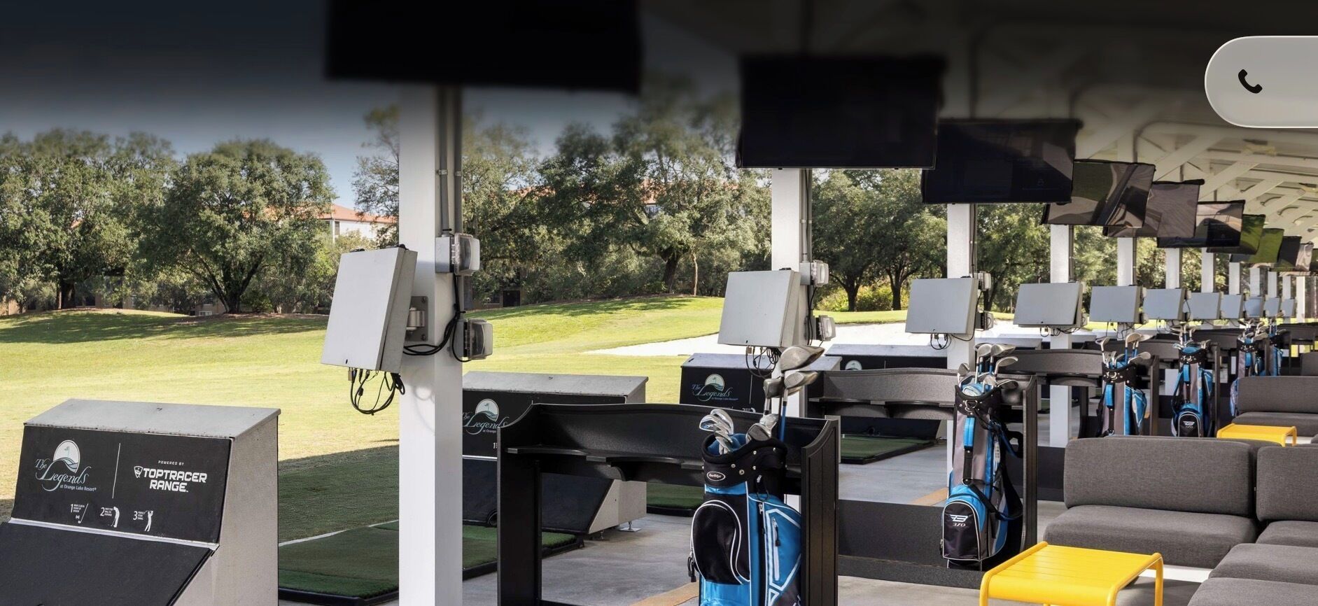 Un campo de prácticas de golf con múltiples plataformas de salida, bolsas de golf y equipo electrónico para registrar los puntajes.