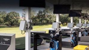 Un parcours d’entraînement au golf doté de plusieurs zones de départ, de sacs de golf et d’un système électronique de suivi des scores.