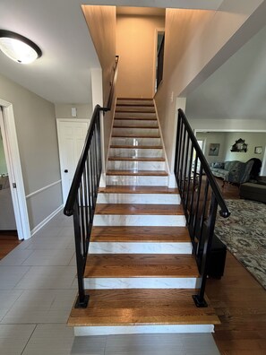 A staircase with wooden steps and black railings, leading to a landing with a ceiling light.