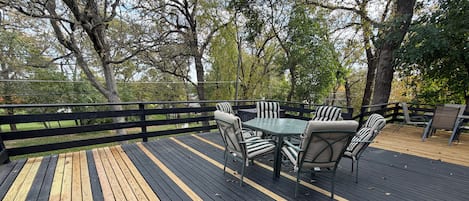 A wooden deck with a table and chairs, surrounded by a black railing.