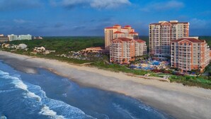 Ein Strandhotel mit mehreren Hochhäusern, einem Sandstrand und einem Poolbereich.