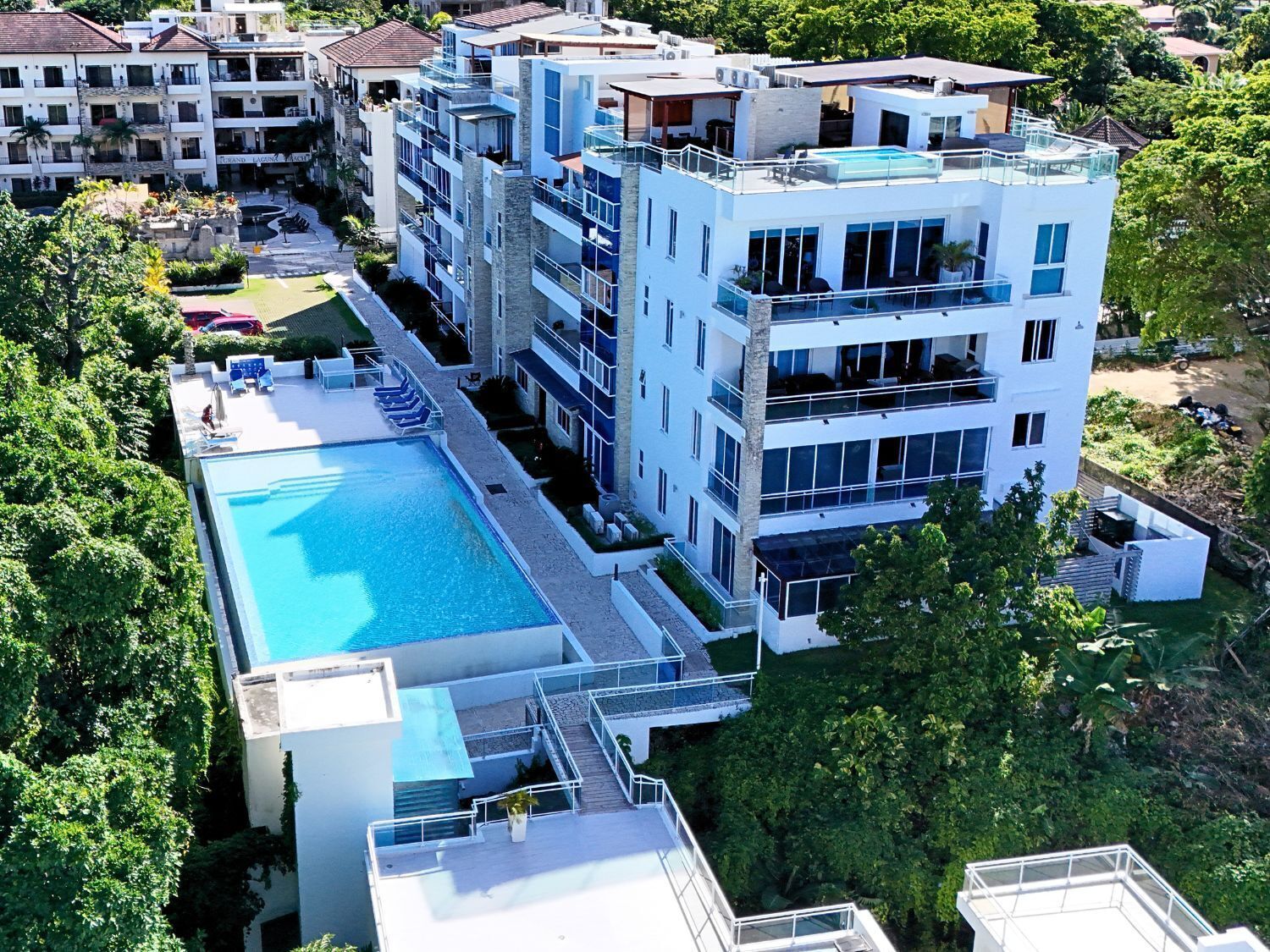 Un hotel de varios pisos con piscina en la azotea y zona de estar exterior.