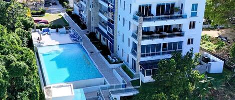 Un hotel de varios pisos con piscina en la azotea y zona de estar exterior.