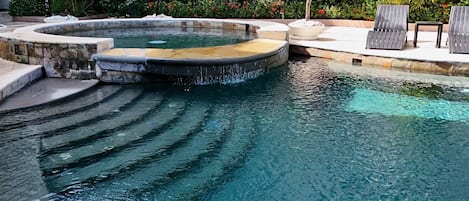 Une piscine à bords incurvés agrémentée d’une petite cascade.
