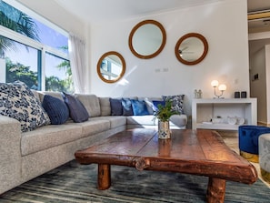 A modern living room with a sectional sofa, a wooden coffee table, and three wall-mounted mirrors.