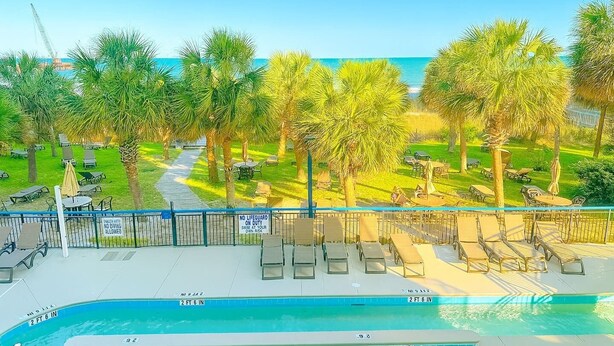 A pool area with lounge chairs and a view of the ocean. - BOARDWALK BLISS/GREAT LOCATION (Myrtle Beach)