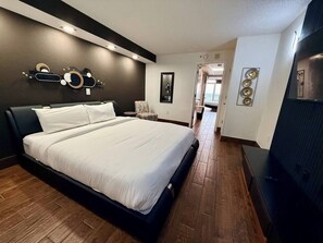 A modern bedroom with a large bed, dark headboard, and a wooden floor. - BOARDWALK BLISS/GREAT LOCATION (Myrtle Beach)