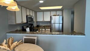 Una cocina moderna con encimeras de granito, electrodomésticos de acero inoxidable y un comedor con una mesa redonda y sillas.