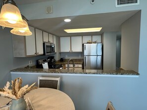 Eine moderne Küche mit Granit Arbeitsplatten, Edelstahlgeräten und einem Essbereich mit rundem Tisch und Stühlen.