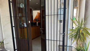 Een receptiezone met een gesloten metalen hek, een receptiebalie en potplanten.